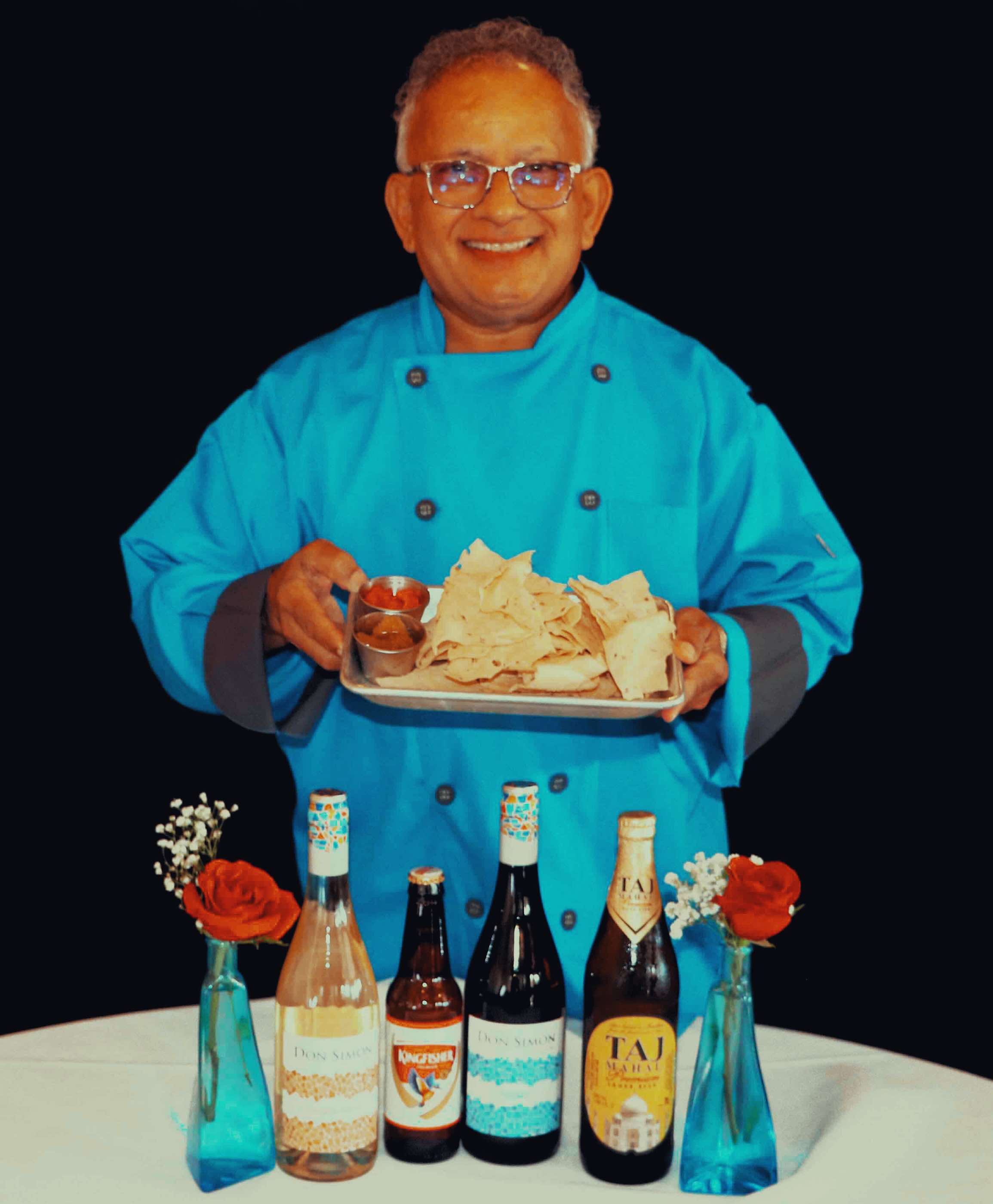 Guru Indian Restaurant's Chef and Owner Uday Kadam holding appetizers and drinks available at Guru Indian Restaurant